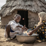 Mahamat y Sara se lavan las manos en la puerta de su vivienda en la comunidad de Kamkalaga. En esta región de Chad donde los recursos hídricos son muy escasos Oxfam Intermón ha rehabilitado dos pozos de agua y ha instalado un tanque en el centro de salud.