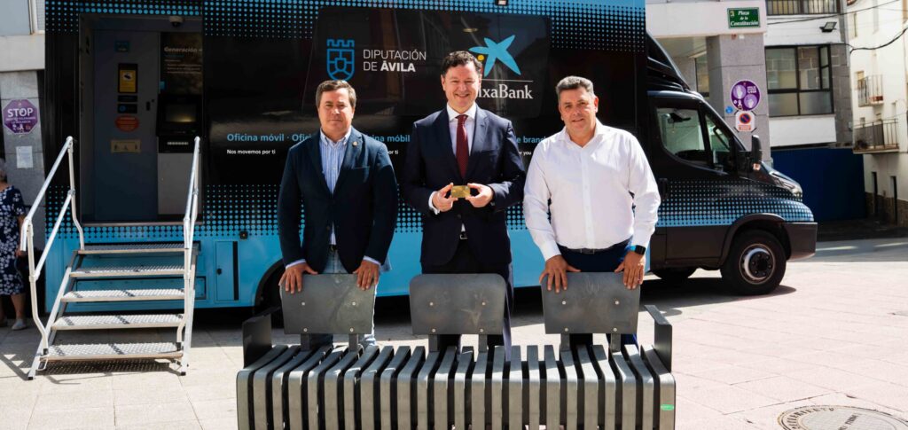 El director territorial de CaixaBank en Castilla y León, Gerardo Cuartero (centro); el vicepresidente primero de la Diputación de Ávila, Jesús Martín (izda.), y el alcalde de Serranillos, Carlos Cayuela (dcha.), con uno de los bancos realizados con tarjetas recicladas