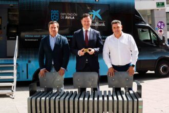 El director territorial de CaixaBank en Castilla y León, Gerardo Cuartero (centro); el vicepresidente primero de la Diputación de Ávila, Jesús Martín (izda.), y el alcalde de Serranillos, Carlos Cayuela (dcha.), con uno de los bancos realizados con tarjetas recicladas