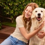 Una mujer sentada junto a un perro en una zona ajardinada. Imagen de Stock cedida por CaixaBank